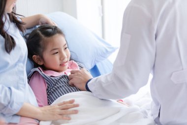 Pediyatrist doktor kalp atışlarını kontrol etmek için steteskop kullanıyor..