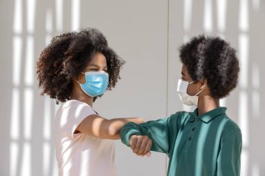 Afro çocuklar koruyucu maskeli kıvırcık saçlar binanın gölgeli saçlarının altında insanlar koronavirüsün yayılmasını önlemek için koruyucu maskeler takıyor..
