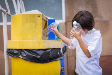 Çevreyi kurtarmak için sevgi kavramı. Çocuklar plastik su şişeleri topluyor ve çöp kutusuna boş plastik şişe atıyor. Çevre dostu kavram..