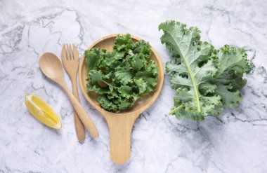 Tahta tepside limonla servis edilen yeşil lahana karışımıyla dolu berrak bir bardak..