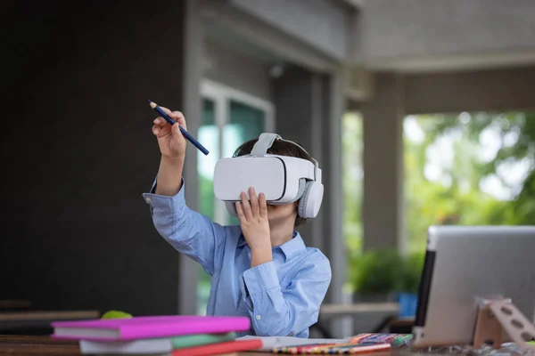 Child boy wears VR glasses (Virtual reality glasses).He is drawing on air follow visible image in side VR glassessmarthphone in side connect by application.3D gadget technology.