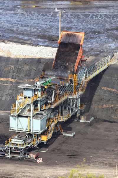Heavy construction tipper trucks dump coal to the conveyor at co — Stock Photo, Image