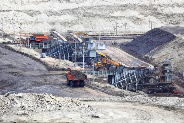Heavy construction tipper trucks dump coal to the conveyor at co — Stock Photo, Image