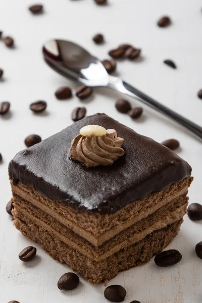 Ciasto czekoladowe i ziarna kawy na stole — Zdjęcie stockowe