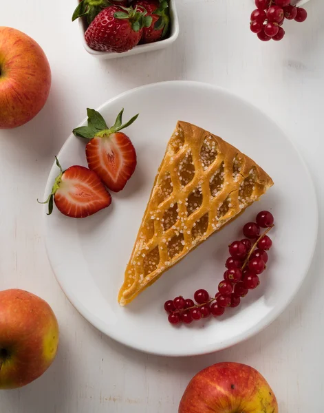 Ломтик яблочного пирога на белой тарелке с фруктами — стоковое фото
