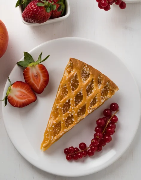 Ломтик яблочного пирога на белой тарелке с фруктами — стоковое фото