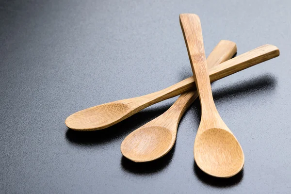 Wooden spoons on black table — Stock Photo, Image