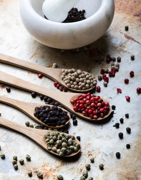 Color peppercorn seeds on wooden spoons Royalty Free Stock Images