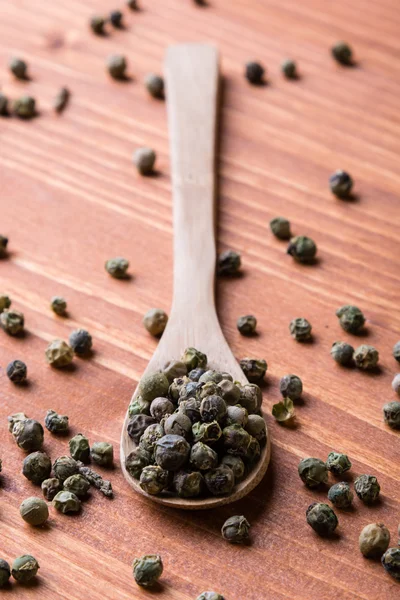 Semillas de pimienta verde sobre mesa de madera — Foto de Stock