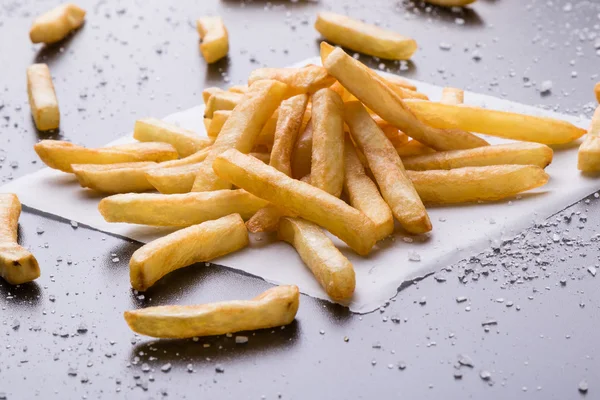Patatine fritte su un tavolo nero con sale marino — Foto Stock