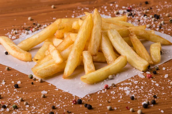 Pommes frites på ett träbord med smaksättning — Stockfoto