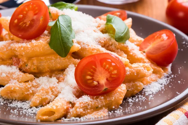 Penne con tomate en plato marrón — Foto de Stock