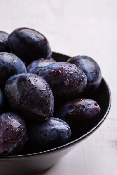Fresh plums in black bowl — Stock Photo, Image