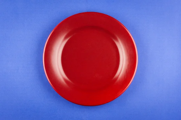 Червона тарілка на синьому столі — стокове фото