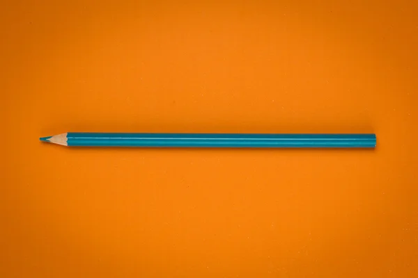 Lápiz azul sobre papel naranja — Foto de Stock