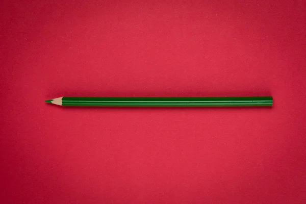 Green pencil on red paper — Stock Photo, Image