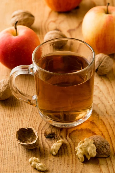 Té con manzanas y nueces en la mesa de madera — Foto de Stock