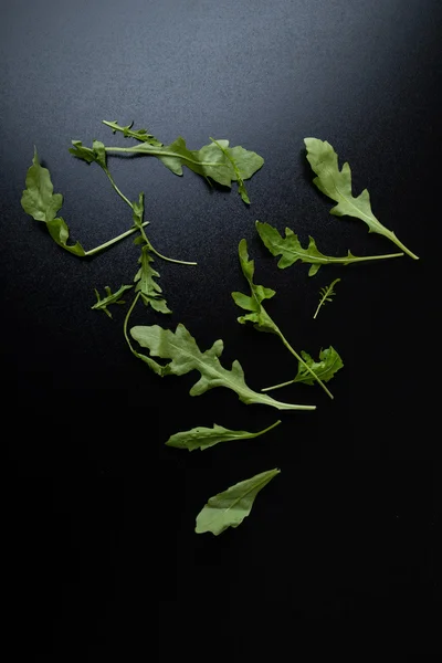 Feuilles de rucola sur une table noire — Photo