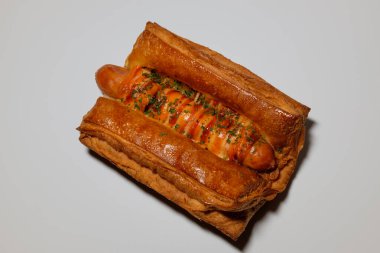 Sosisli börek. Yumuşak hamur işi. Üzerine sos serpiştirilmiş ekmek.