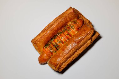 Sosisli börek. Yumuşak hamur işi. Üzerine sos serpiştirilmiş ekmek.