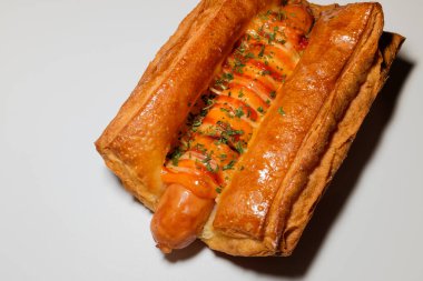 Sosisli börek. Yumuşak hamur işi. Üzerine sos serpiştirilmiş ekmek.