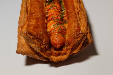 Sosisli börek. Yumuşak hamur işi. Üzerine sos serpiştirilmiş ekmek.