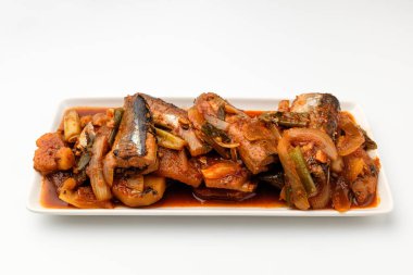 Kimçi ve saury soslu çorba tabağı. Balık ve sebzeli Kore yemeği. İçinde yeşil soğan, soğan, patates ve turp bulunan bir yemek.