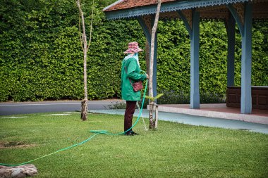 Bangkok, Tayland 04.07.2021 Tayland işçisi Bangkok 'taki Antik Şehir Parkı' ndaki çimleri suluyor