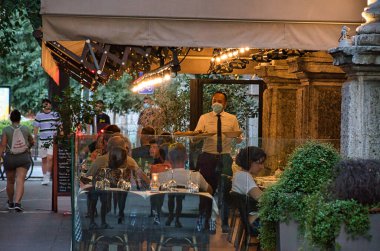 Milan, İtalya 08.27.2021 İnsanlar, turist eski, geleneksel bir İtalyan restoranında yemek yiyor.