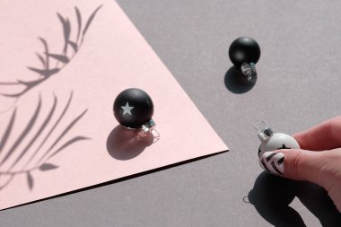 Xmas modaya uygun bir geçmiş. Sıcak pembe ve gri katmanlı kağıt üzerinde siyah beyaz Noel süsleri. Kağıt, top ve palmiye yapraklarının gölgeleriyle Geometrik düzenleme.