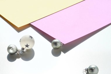 Moda Xmas dekoru. Mor, beyaz ve sarı katmanlı kağıtta siyah beyaz Noel süsleri. Topların ve palmiye yapraklarının gölgeleriyle en düşük bileşim.