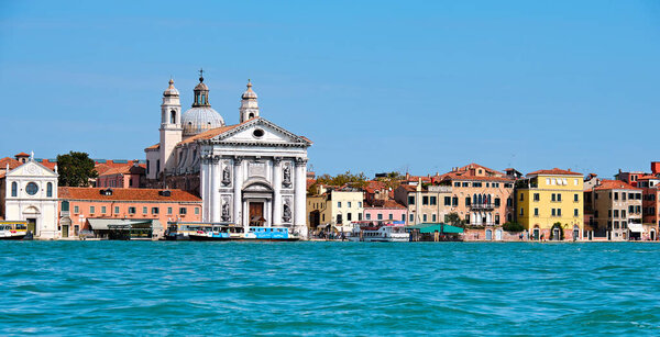 VENICE, ITALY - SEPTEMBER 20, 2020: Panoramic view on the Venice lagoon with vaporetto boats moored by a stop by Gesuati Church. The city is looking for new approaches for transport and hospitality industries beyond mass tourism.
