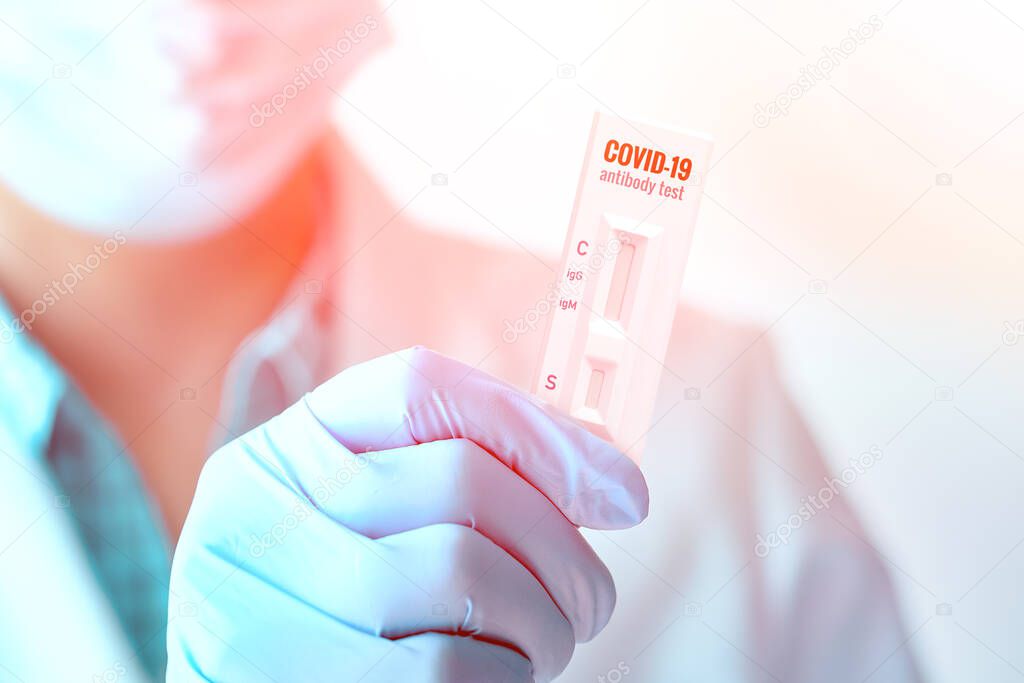 Medic shows rapid laboratory COVID-19 test for detection of specific antibodies to Novel Coronavirus, SARS-CoV-2. Plastic text in gloved hand.