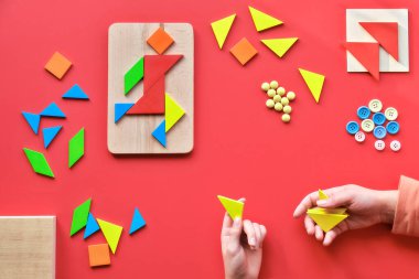 2 Nisan Dünya Otizm Günü için yaratıcı tasarım. Tangram elementleri, çalışan adamın piktogramında düzenlenmiş düğmeler ve kırmızı arkaplana saçılmış.