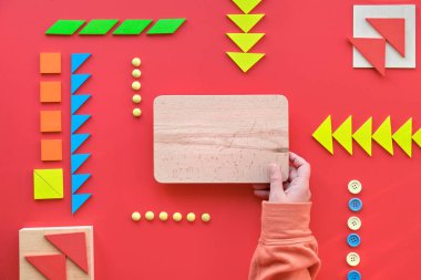 2 Nisan Dünya Otizm Günü için yaratıcı tasarım. Metin alanı olan ahşap tahtayı tut. Tangram ögeleri, kırmızı arkaplanda sıralı düğmeler.