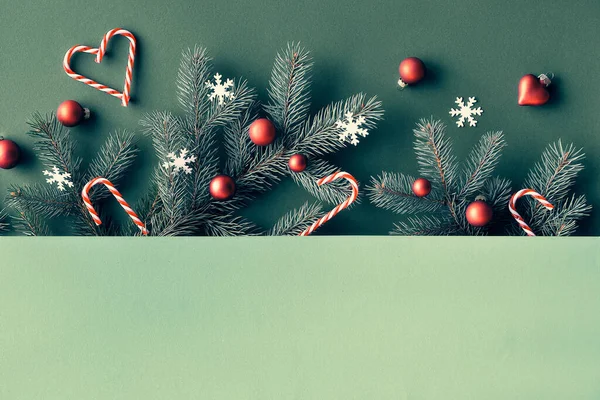 コピースペースと緑の紙の上の2つのトーンクリスマスのお祝いの背景 トップビュー モミの小枝のパノラマバナー画像 赤い泡 キャンディーの杖 雪の結晶 — ストック写真