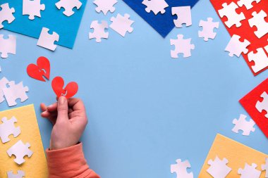 2 Nisan Dünya Otizm Farkındalık Günü için yaratıcı tasarım. Kağıttan kalp şeklinde elle tutulur. Katmanlı keçeli kumaş parçaları üzerindeki yapboz elemanı. Düz konum, üst görünüm, yaratıcı arkaplan, metin alanı.