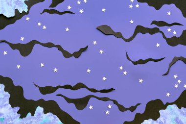 Night background with watercolor clouds, light blue and black. White stars cut from paper. Creative top view. Concept flat lay for quality of sleep topic, quiet night time with sweet dreams.