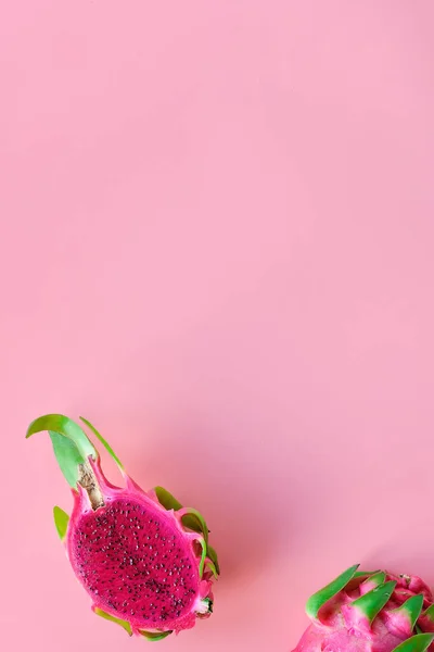 Fresh organic pink dragon fruit, pitaya or pitahaya with pink middle. Trendy top view on pink background with text space.