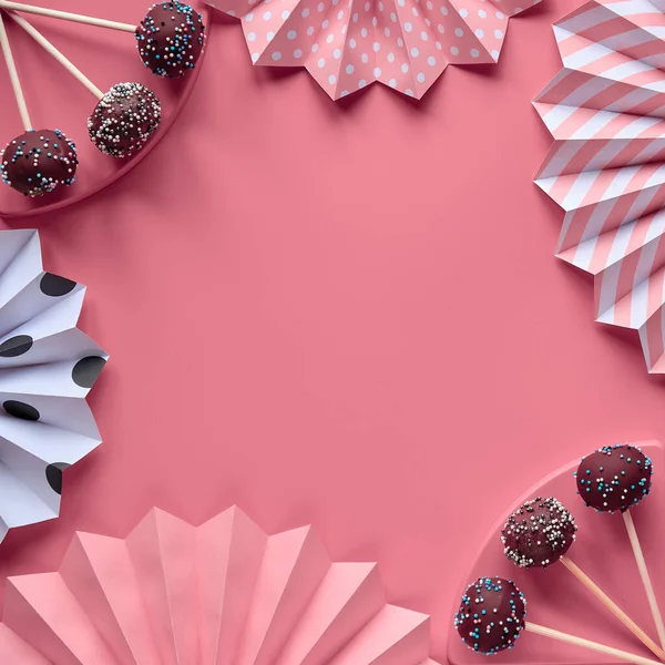 带有文字空间的装饰正方形框架 盖满巧克力和彩色糖霜的蛋糕创新的单色平铺在粉红色的纸上 上面装饰着美味的蛋糕和折起来的纸扇 — 图库照片