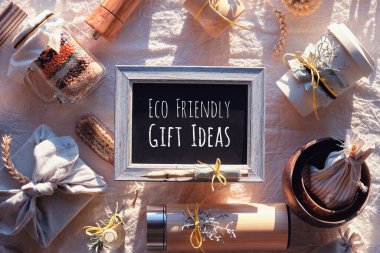 Eco Frift hediye fikirli karatahta. Sıfır noel hediyeleriyle yatıyordu. Havluya sarılı Noel hediyesi, bambu kapları, kaseler, yalıtılmış matara. Tarafsız keten tekstil üzerinde sürdürülebilir sunumlar.