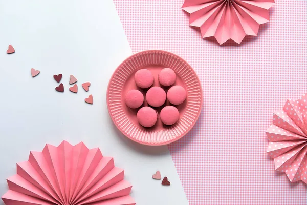 創造的な食品コンセプト プレートの上の甘いピンクのマカロン モノクロームフラットレイ上の分割2トーンピンク白の背景とともに折り畳まれた紙のファン — ストック写真