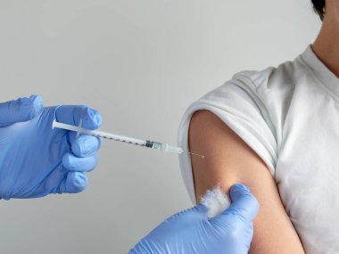 Ellerine şırınga ve omzuna sahip eldiven tak, genç çocuk. Coronavirus, grip ya da kızamık aşısı konsepti. Sıhhiye, doktor, hemşire, sağlık uygulayıcısı okul çocuğunu aşıladı.