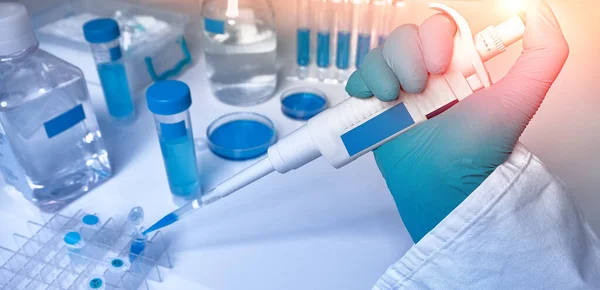 Hand in glove with automatic pipette and samples, panoramic image. Polymerase Chain Reaction PCR used in medical testing, biochemistry, molecular biology, genetics, clinical research in lab.