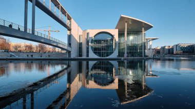 BERLİN, ALMANY - 14 Şubat 2021: Pier Paul-Loebe-Haus Reichstag. Spree Nehri üzerindeki yaya köprüsünden panoramik kış manzarası. Sakin bir akşam, yansımalı su, buzlu su.
