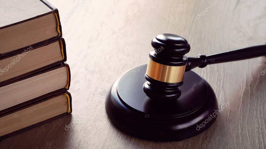 Old white phone and law hammer on wooden table with long shadows. Concept of legal advice, consultation, counseling over the phone.