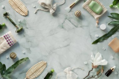Güzellik masajı için yeşim yüz silindiri, cilt bakımı ürünleri. Gerekli yağ şişesi. Beyaz mermer masanın üzerinde yatıyordu. Manolya çiçekleri, yeşil nesneler. Üst görünüm, kopyalama alanı, metin yeri.