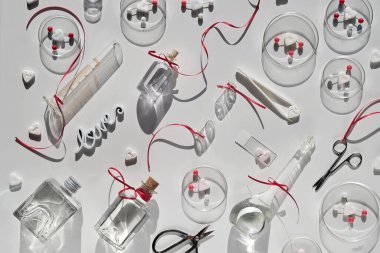 Aşkın kimyası. Yaratıcı düz yatak, kimyasal camlı üst manzara, petri kapları, aşk molekülleri, şeker kalpler, makas, pens, aşk iksirleri. Romantik duyguları incele. Güneş ışığı, uzun gölgeler.