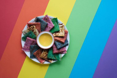 Gökkuşağı krepleri, farklı renkte krepler. Ispanak, pancar tozu, mavi kibrit ve zerdeçal krepleri. Renkli krepler, gökkuşağı renkli kağıdın üzerinde düz uzanmış. Kopyalama alanı, metin için yer.