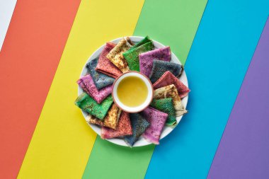 Gökkuşağı krepleri, farklı renkte krepler. Ispanak, pancar tozu, mavi kibrit ve zerdeçal krepleri. Renkli krepler, katmanlı kağıdın üstüne gökkuşağı renginde serilmiş. Kopyalama alanı, metin için yer.